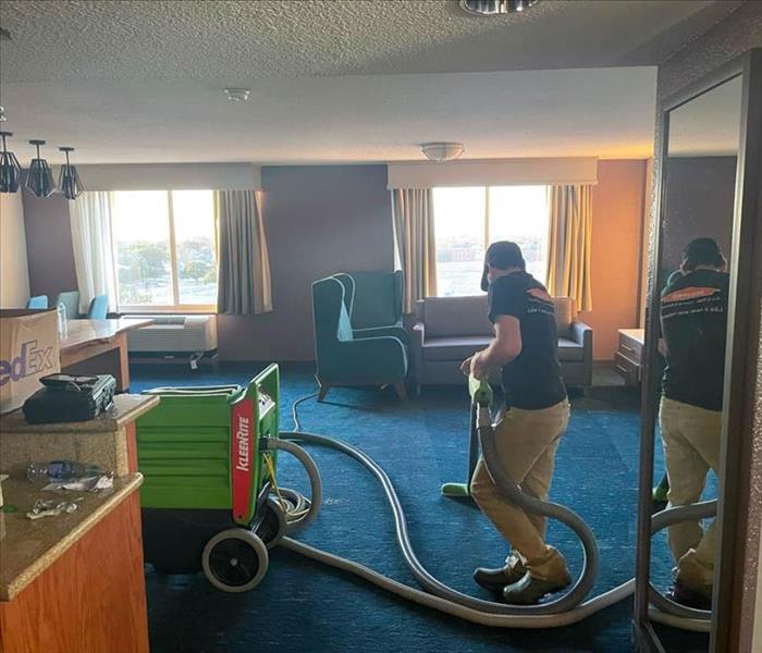 SERVPRO employee cleaning the damages in room