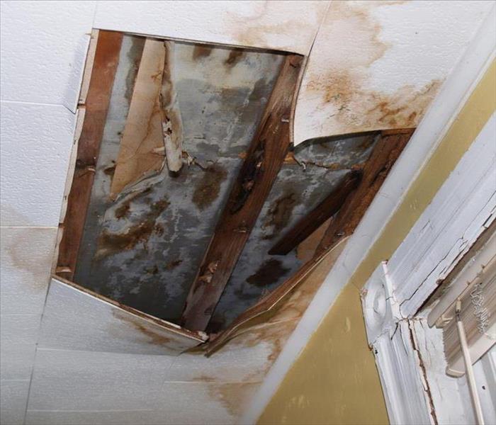 Collapsed ceiling surrounded by water stains.